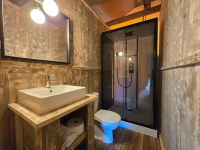 a kitchen with a sink and an orange wall at Camping Costa Dorada Tienda Aura in Canet de Mar