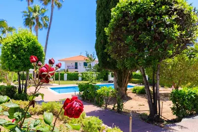a garden with red flowers and a swimming pool at Villa Carmen - Peaceful Eco-Luxury with private pool in Cunit