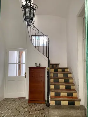 a staircase with a chandelier next to a door at Casa l'àvia - Sant Pol de Mar in San Pol de Mar