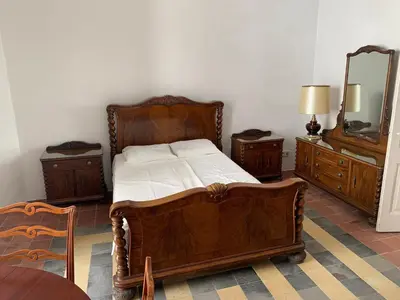 a bedroom with a wooden bed and two dressers and a mirror at Casa l'àvia - Sant Pol de Mar in San Pol de Mar