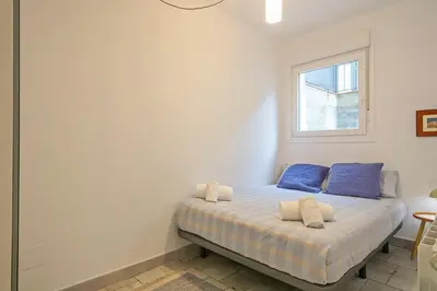 a bedroom with a bed with blue pillows and a window at Winahost Apartament Cirerer in Valldoreix