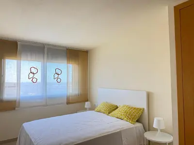 a bedroom with a bed with yellow pillows and a window at Dúplex con encanto en Castelldefels in Castelldefels