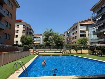 a group of people in a swimming pool with buildings at Dúplex con encanto en Castelldefels in Castelldefels