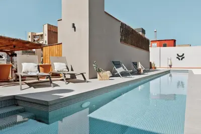 a swimming pool with chairs and a building at Tenere - 1 bedroom and pool in Gràcia in Barcelona
