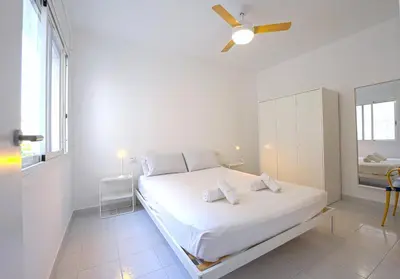 a white bedroom with a bed and a window at Winahost Barcelona Sants in Barcelona