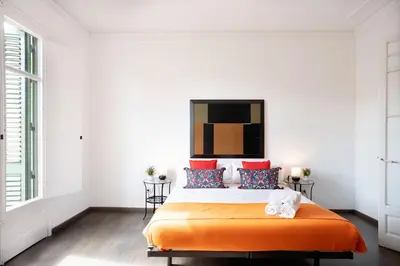a white bedroom with an orange bed with red pillows at Apartamento Premium 5 Hab con Balcón a Gran Vía - Grupos hasta 10 - Passeig Gràcia 7min in Barcelona