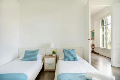 two beds in a white room with blue pillows at Apartamento Premium 5 Hab con Balcón a Gran Vía - Grupos hasta 10 - Passeig Gràcia 7min in Barcelona