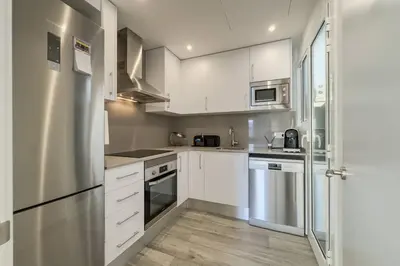a kitchen with white cabinets and a stainless steel refrigerator at Comfort, Style & Value near Barceloneta Beaches in Barcelona