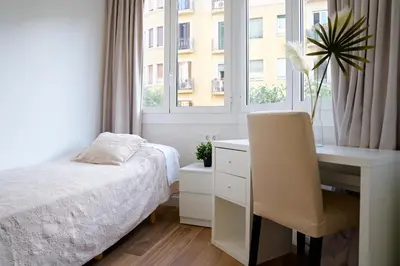 a bedroom with a bed and a desk and a window at Apartamentos Valentin in Barcelona