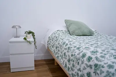a bedroom with a bed with a green blanket and a night stand at Apartamentos Valentin in Barcelona
