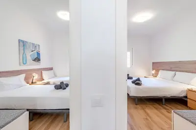 two beds in a room with white walls and wooden floors at Key Barcelona Sagrada Familia House Terrace in Barcelona