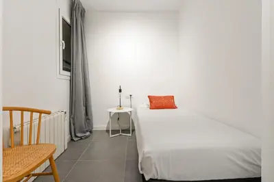 a white bedroom with a bed and a chair at Flateli Espronceda 01 in Barcelona