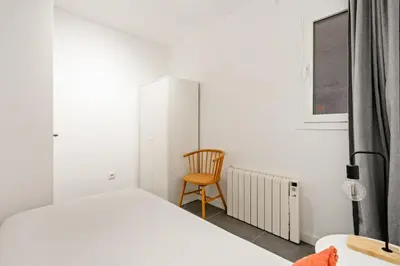 a bedroom with a bed and a chair next to a window at Flateli Espronceda 11 in Barcelona