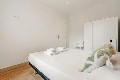 a white bedroom with a bed with a dragon toy on it at Flateli Espronceda 32 in Barcelona