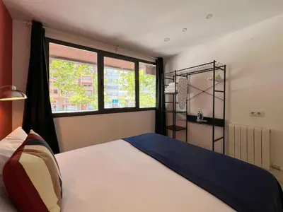 a bedroom with a bed and a large window at Stay U-nique Apartment Roma in Barcelona