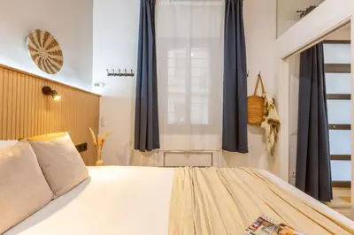 a bedroom with a large bed with blue curtains at Lodging Apartments Almirall Beach B1 in Barcelona