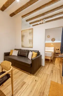 a living room with a leather couch and a bedroom at Lodging Apartments Almirall Beach B1 in Barcelona