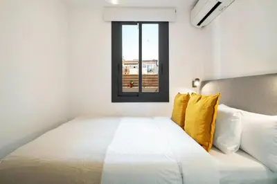 a white bed with yellow pillows and a window at Stay U-nique Tapioles Central Apartment in Barcelona
