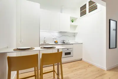 a white kitchen with two chairs and a counter at Art House Travessera de Gràcia-2 in Barcelona