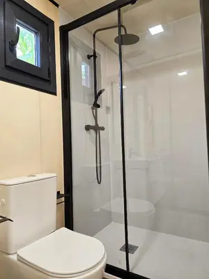 a bathroom with a toilet and a glass shower at Costa Dorada Tiny Amaia in Canet de Mar