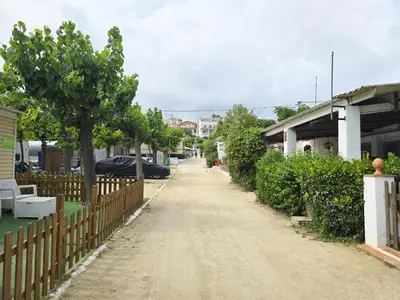 a dirt road with a fence and trees and houses at Costa Dorada Tiny Amaia in Canet de Mar