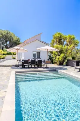 a pool with tables and umbrellas in front of a house at Yasmine Casas Barcelona in Olivella
