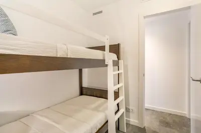 a bunk bed room with two bunk beds and a ladder at SeaSunSand Apartment in San Pol de Mar