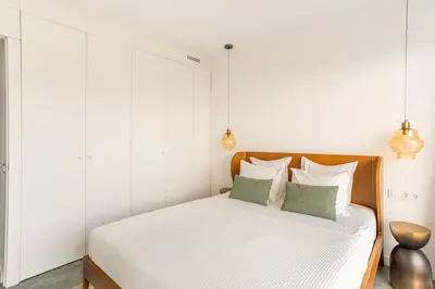 a bedroom with a white bed with two green pillows at SeaSunSand Apartment in San Pol de Mar
