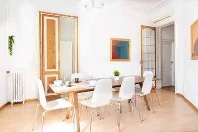 a dining room with a wooden table and white chairs at Apartamento de Lujo 7 Hab con balcón en Gran Vía -Grupos hasta 14 - 8min a pie Passeig Gràcia in Barcelona