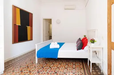 a bedroom with a bed and a painting on the wall at Apartamento de Lujo 7 Hab con balcón en Gran Vía -Grupos hasta 14 - 8min a pie Passeig Gràcia in Barcelona