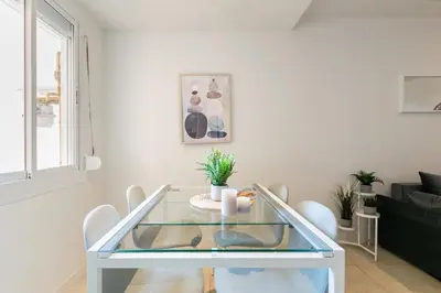 a white living room with a glass table and chairs at Furnished & Fully Equipped 2BR near the beach in Barcelona