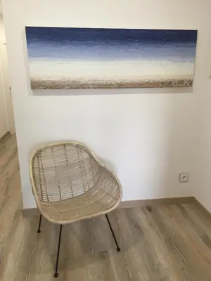 a wicker chair sitting in front of a painting at Rustic good in Sitges