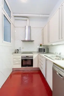 a kitchen with white cabinets and a red floor at Luxury Business Apartment Gran Vía - 2 rooms - Romantic Eixample - 8min Passeig Gràcia in Barcelona