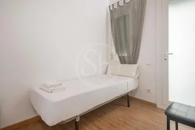 a bedroom with a bed and a chair and a window at Apartamento familiar en Barcelona in Barcelona
