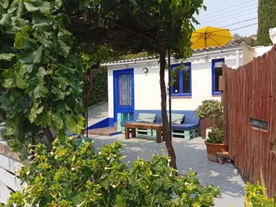 a blue and white house with a bench and an umbrella at El Portal, 12 mins from Sitges in Olivella