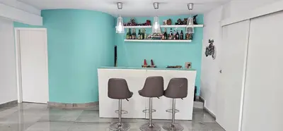 a bar with two stools in a room with a blue wall at The Family Palace in Piera