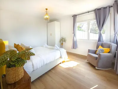 a bedroom with a bed and a chair and a window at Mikasi Hills by Hello Homes Sitges in Sant Pere de Ribes