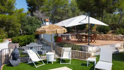 a patio with a statue and chairs and an umbrella at Mikasi Hills by Hello Homes Sitges in Sant Pere de Ribes