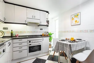 a kitchen with white appliances and a table with chairs at Apartamento Moderno con Balcón Meridiana Barcelona in Barcelona