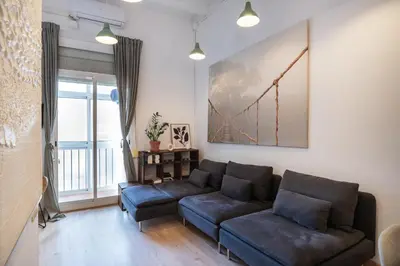 a living room with a couch and a bridge painting on the wall at Charm and Comfort in the Heart of Sant Antoni, Barcelona in Barcelona
