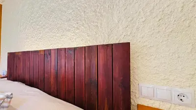 a bed with a wooden headboard next to a wall at Apartament rural in San Martín Sarroca