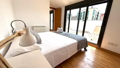 a bedroom with a white bed and a large window at Dúplex zona olimpica by Prestigi in Terrassa