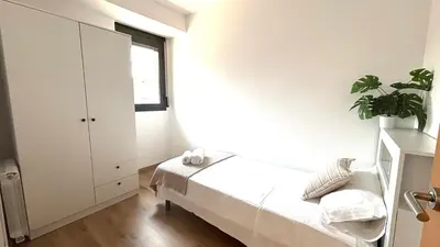 a white bedroom with a bed and a window at Dúplex zona olimpica by Prestigi in Terrassa
