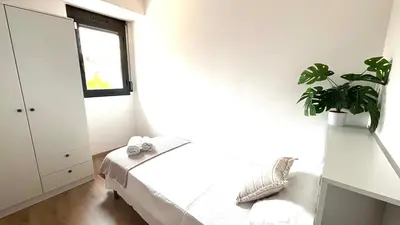 a white bedroom with a plant on the wall at Dúplex zona olimpica by Prestigi in Terrassa