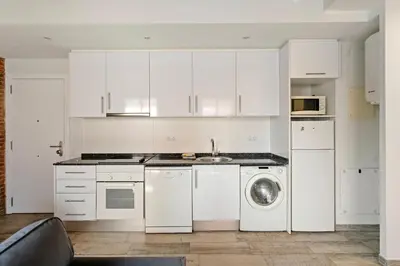 a kitchen with white cabinets and a washing machine at Sants Apartment in Barcelona