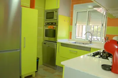 a green kitchen with a sink and a microwave at casa vacacional con piscina privada in Sant Cebrià de Vallalta