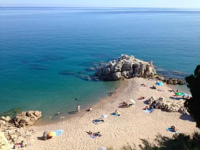 a group of people on a beach near the water at Casa familiar con piscina cerca del mar y montaña in San Pol de Mar