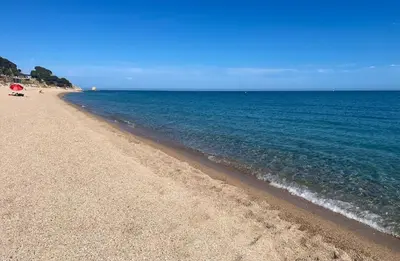 a beach with a red umbrella and the ocean at Casa familiar con piscina cerca del mar y montaña in San Pol de Mar