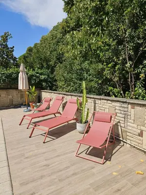a row of pink lounge chairs on a patio at Poolside Apartment Barcelona Sant Cugat in Sant Cugat del Vallès
