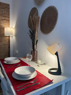 a table with a red table cloth and plates and a lamp at Barceloneta Love 1 min to the beach in Barcelona